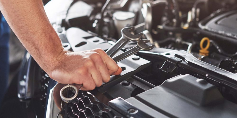 Picture showing muscular car service worker repairing vehicle.